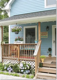 a blue house with flowers on the front porch