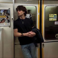 a young man leaning against the door of a subway car with his arm wrapped around him