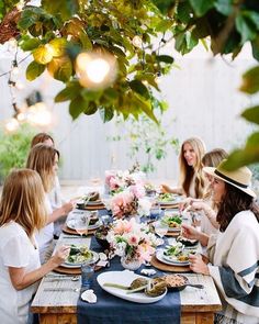 a group of women sitting around a table eating food