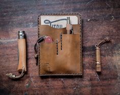 a leather wallet with tools in it sitting on a wooden table next to an open pocket knife