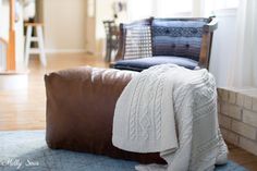 a brown leather chair with a white blanket on it and a blue rug in the background