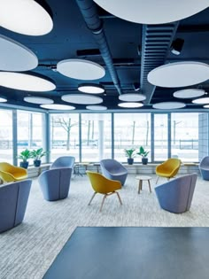 an empty conference room with blue and yellow chairs, round lights, and potted plants