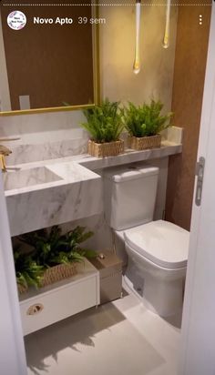 a white toilet sitting next to a sink in a bathroom under a mirror and lights