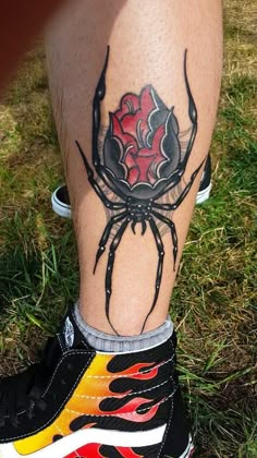 a spider tattoo on the leg of a person's legs, with flames coming out of it