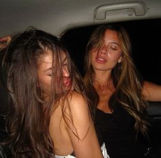 two women sitting in the back seat of a car