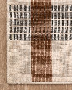 a brown and white checkered rug on top of a wooden floor next to a wall