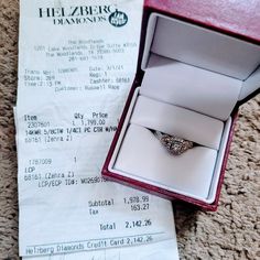 a diamond ring sits in a box on the floor next to a receipt for $ 1, 500