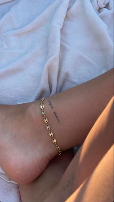 a close up of a person's foot with a gold chain on it