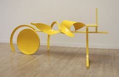 a yellow table sitting on top of a hard wood floor next to a white wall