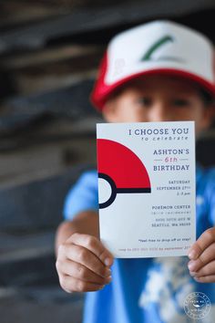 a young boy holding up a pokemon birthday card