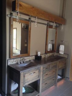 a bathroom with two sinks, mirrors and lights on the wall above it's counter