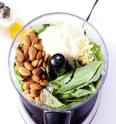 a food processor filled with nuts, spinach leaves and other ingredients to make a salad