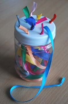 a jar filled with colorful streamers on top of a wooden table next to a toothbrush