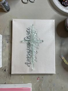 a cross made out of glass sitting on top of a table next to scissors and other crafting supplies