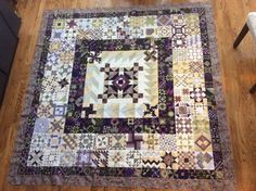 a quilt is laying on the floor in front of a chair and table topper