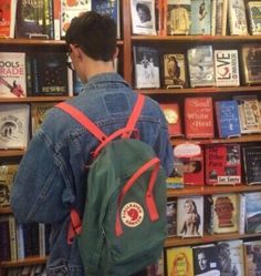 a man with a backpack looking at books in a book store on the shelf behind him