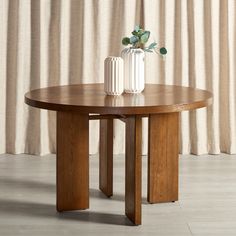 a round wooden table with two vases on it