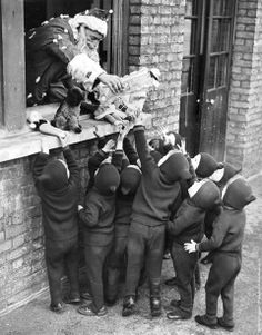 a group of children standing next to each other in front of a brick wall and window