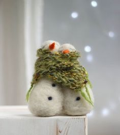 two small stuffed animals sitting on top of a wooden block with lights in the background