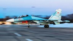 a fighter jet taking off from an airport runway at dusk with blurry trees in the background