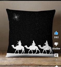 a black and white pillow with three wise men riding on camels in the night sky