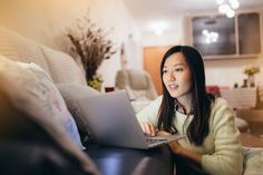 a woman sitting on a couch using a laptop computer