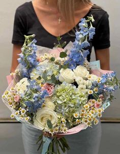 a woman holding a bouquet of white and blue flowers