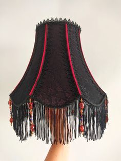 a lamp shade with tassels and beads hanging from it's side on a person's hand