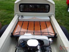 an engine compartment in the back of a white pickup truck with wood flooring on it