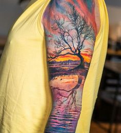 a man's arm with a tree and water scene tattoo on the left sleeve