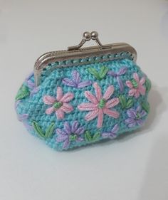 a crocheted purse with flowers on it sitting on a white counter top next to a keychain