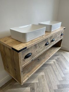 two white bowls are sitting on top of a wooden cabinet next to a wall mounted sink