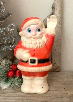 a santa clause figurine sitting on top of a shelf next to a christmas tree