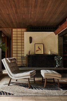 a chair and ottoman in a room with wood paneling on the ceiling, along with a fireplace