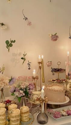 a table filled with cakes and cupcakes on top of each other next to candles