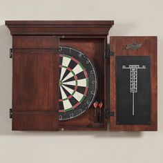 a dart and darts in a wooden box on the wall with chalkboard attached to it