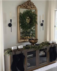 a christmas mantle with stockings and candles on it in front of a mirror that is hung above the fireplace