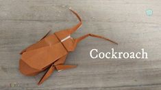 an origami cockroach sitting on top of a wooden table with the word cockroach written below it