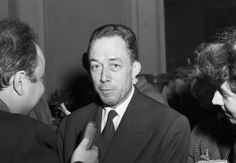 black and white photograph of man in suit talking to two women