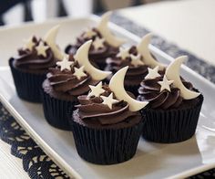 chocolate cupcakes decorated with white stars and crescent moon frosting on a plate