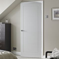 a bedroom with a bed, dresser and white door