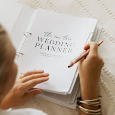 a woman is writing on a wedding planner