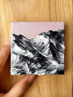 a hand holding up a piece of art that looks like mountains in black and white