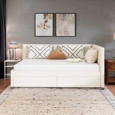 a living room with a white couch and two framed pictures on the wall above it