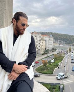 a man sitting on top of a building with his arms crossed and looking down at the street