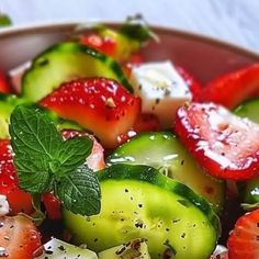 a bowl filled with cucumbers, strawberries and mint