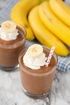 two glasses filled with chocolate pudding and banana's next to each other on a table