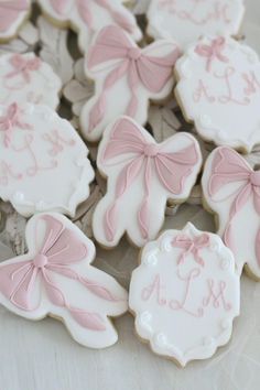 decorated cookies with pink bows and monograms are displayed on a white tablecloth