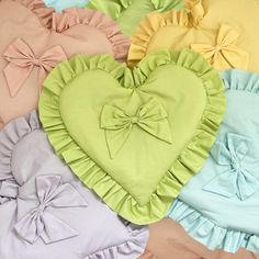 a heart shaped pillow with ruffles and bows on the front in pastel colors