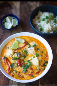 a bowl of fish curry with rice and limes